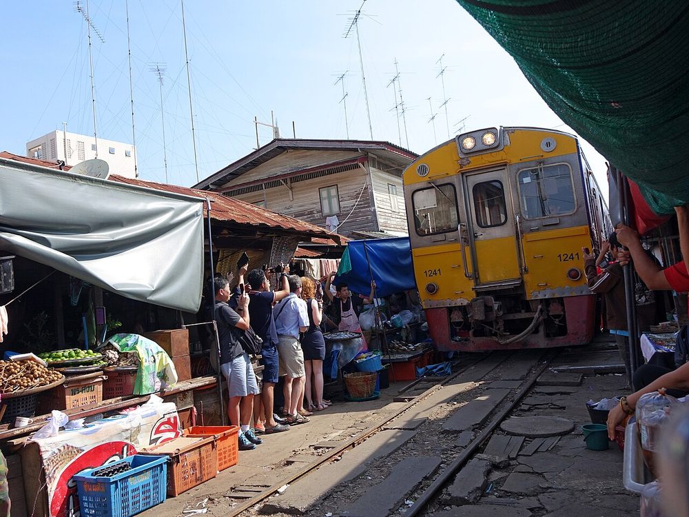 A train passing through the stalls of Maeklong Railway Market